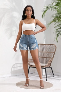 Detail of high waisted blue denim shorts with distressed frayed hem and ripped accents
