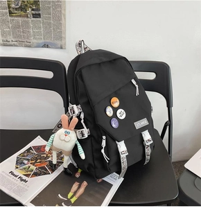 Detail of black tactical backpack with stylish badges and cute rabbit charm on a chair