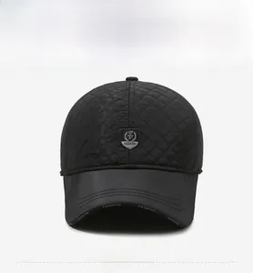 Detail of black quilted baseball cap featuring a shield patch and faux leather brim texture