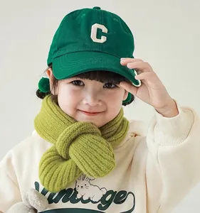 Detail of green knitted ribbed scarf and canvas baseball cap for toddlers