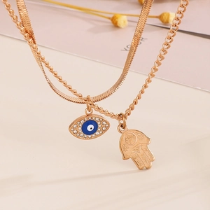 Double-layered golden necklace with Hamsa hand and blue Evil Eye pendants with crystals