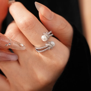 Detailed close-up of a knotted pearl ring with zircon accents on a woman's finger