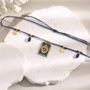 Detail of 18K gold plated crown square pendant with blue rope on decorative stones