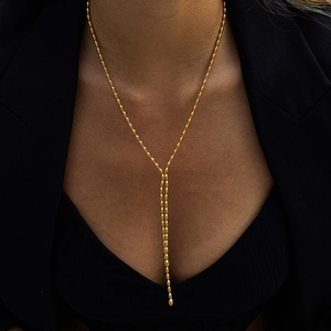 Close-up of golden stainless steel Y-shaped necklace with bead tassel on black blazer