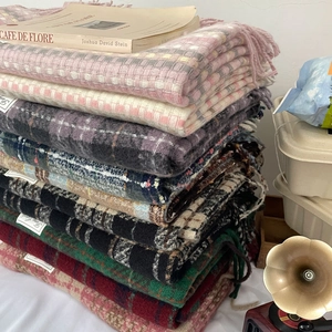 Close-up of stacked colorful plaid scarves with soft fringe and knit texture detail
