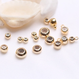 Macro shot of 14k gold-filled beads with silicone inserts on a decorative white shell