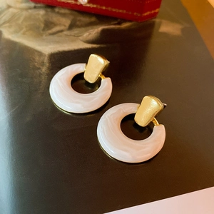 Detailed shot of gold and white marble resin hoop earrings on a magazine background