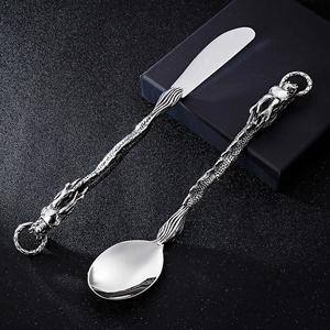 Close-up of silver stainless steel cutlery featuring intricate dragon sculpture handles