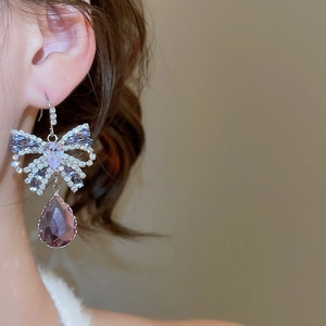 Close-up of butterfly bow earring with sparkling purple teardrop gemstone on ear