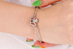 Detailed close-up of a silver crown bracelet with zircons on a spiraled metal band
