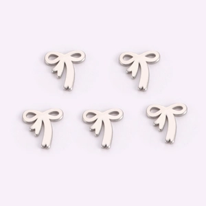 Macro detail of five silver metal bow-shaped pendants on a soft pink background