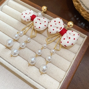 Detail of red polka dot ribbon bow earrings with cascading white pearl tassels
