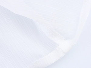 Macro detail of white textured fabric showing fine vertical stripes and stitching quality