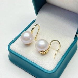 Detailed view of freshwater pearl earrings in a dark green leather jewelry box