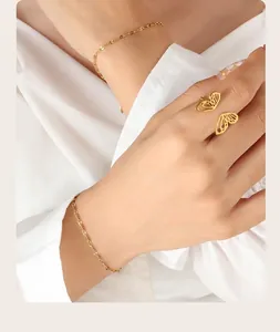 Detailed view of a gold-plated butterfly ring and matching link bracelet on a hand