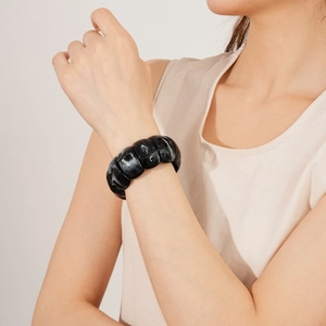 Close-up of a wide geometric acrylic stretch bracelet with black and white marble pattern