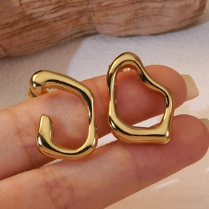 Detailed close-up of wavy gold irregular heart earrings with high polished mirror finish