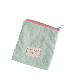 Mint green nylon lipstick pouch with pink zipper and colorful text embroidery label