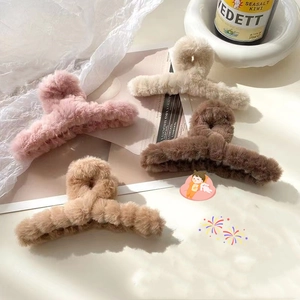 Detailed top view of four large plush hair claws in pink, beige, and brown soft tones