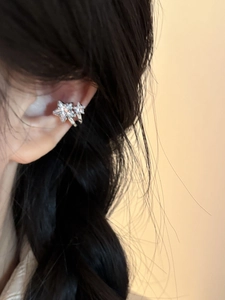 Detail view of silver star ear cuff with zircon crystals on a female model's ear