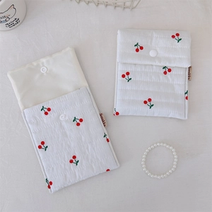 Detail view of two white quilted cherry print fabric pouches with secure snap buttons