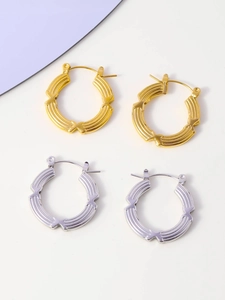 Detail of gold and silver hoop earrings with segment-textured bamboo style finish