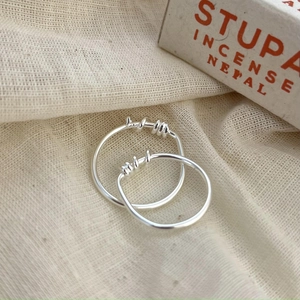 Macro shot of 925 sterling silver twisted irregular rings on rustic linen fabric