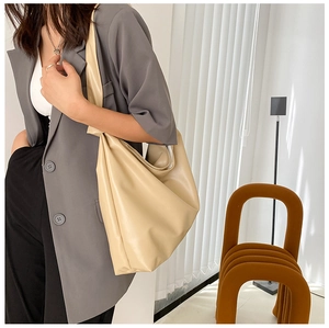 Minimalist beige large capacity shoulder bag shown on shoulder in a modern room setting