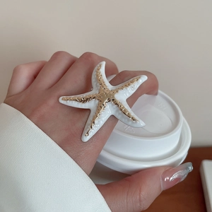 Close-up of a white starfish ring with golden textured center and wrinkled enamel detail