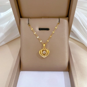 Detail of gold heart pendant with sparkling central zircon and delicate fancy chain