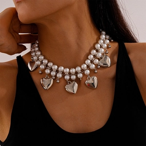 Detail shot of double-layer pearl necklace featuring silver 3D heart pendants on a model
