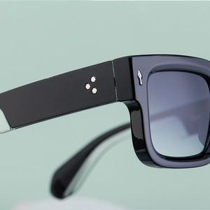 Macro detail of silver arrow accents and star rivets on black square sunglasses frame