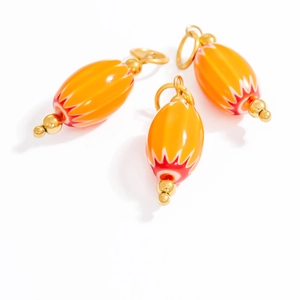 Macro shot of orange striped glass oval pendants with gold metallic ring hardware
