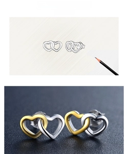 Macro detail of interlocking gold and silver heart-shaped studs on a textured surface