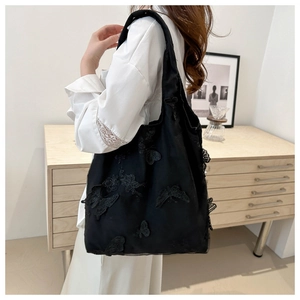 Detailed view of a black mesh tote bag featuring intricate butterfly lace embroidery
