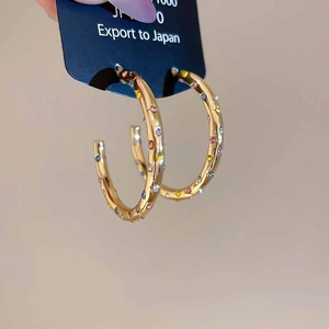 Détail de boucles d'oreilles en C plaquées or avec strass colorés brillants