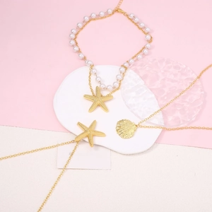 Golden starfish and shell necklace set with imitation pearl accents on a pink background