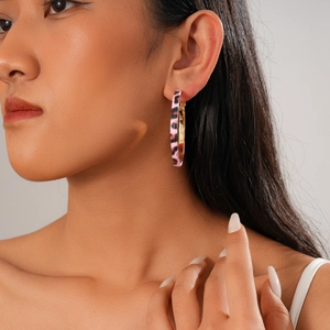 Close-up of a pink leopard print hoop earring with gold inner lining on model