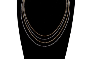 Detailed close-up of minimalist cross chain necklaces in gold and silver on a black display