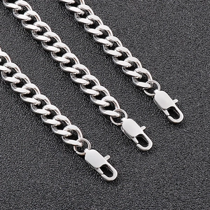 Close-up of polished stainless steel silver chain links with lobster clasps on black surface