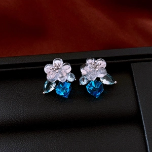 Close-up of vintage flower earrings with blue crystal drops on black leather stand