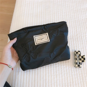 Detail of black bow-knot makeup bag featuring textured fabric and Time to Party label