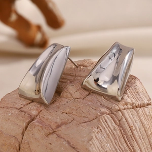 Close-up of silver 316L stainless steel trapezoid earrings on a natural stone base