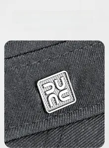Detail of square silver metal logo plaque on dark grey twill outdoor flat top cap