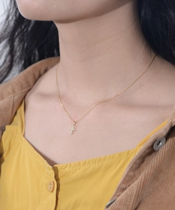 Close-up of elegant gold cross pendant with cubic zirconia stones worn by a model