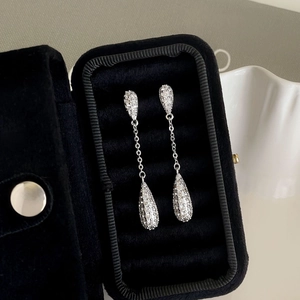 Detailed macro of silver teardrop earrings with pavé zircons in a black velvet jewelry box