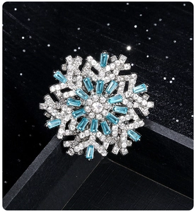 Detail of silver snowflake brooch with blue and clear crystals in black jewelry box