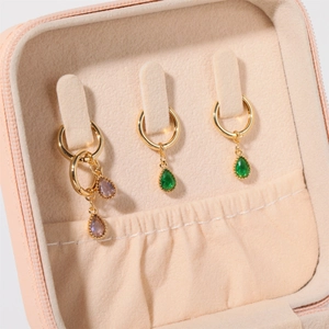 Elegant gold hoop earrings with colorful teardrop gemstones in a pink jewelry travel box