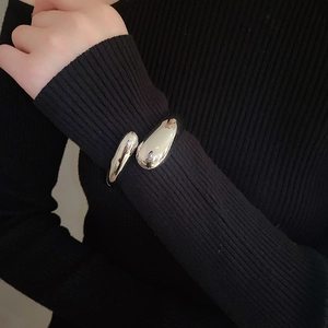 Detailed view of a silver teardrop open cuff bracelet with high-polish mirror finish