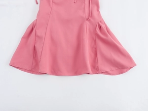 Gros plan de l'ourlet de la robe rose avec tissu tissé lisse et coutures incurvées